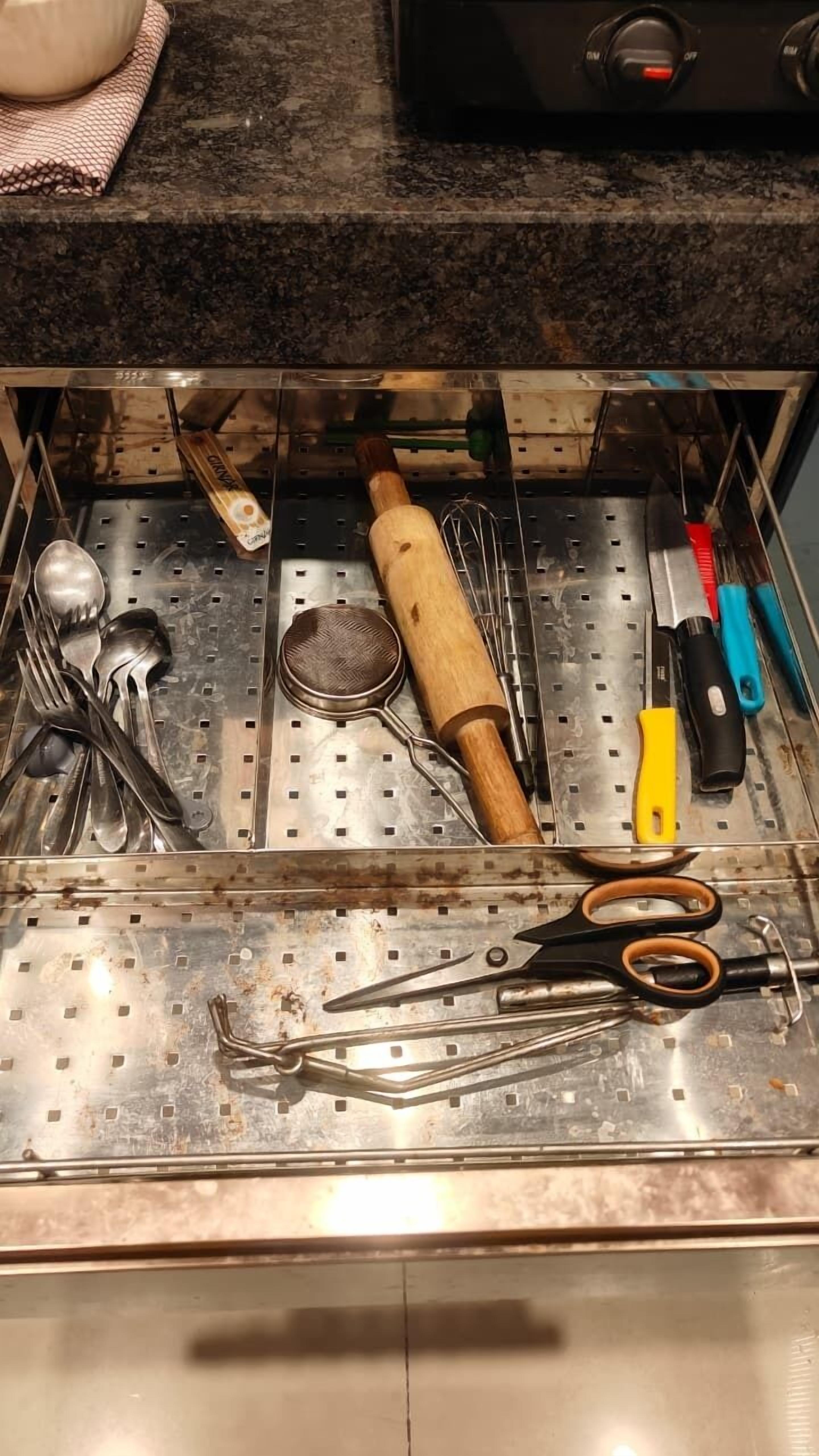 Un tiroir de cuisine contenant des ustensiles et un rouleau à pâtisserie.