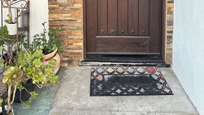 A brown wooden door with a metal handle, a stone wall, a metal bench, and potted plants. - 3-bedroom houseone of the safest areas in Long Beach - Bixby centrally located (Long Beach)