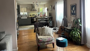 A living room with a floral armchair, a blue ottoman, and a guitar. - 3-bedroom houseone of the safest areas in Long Beach - Bixby centrally located (Long Beach)