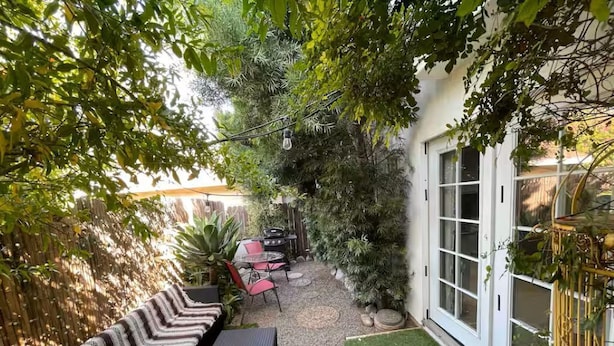 A cozy outdoor patio with a sofa, dining table, and chairs, surrounded by lush greenery and a small garden area. - 3-bedroom houseone of the safest areas in Long Beach - Bixby centrally located (Long Beach)
