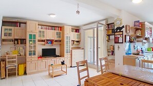 Een kleine keuken met houten kastjes, een eettafel, stoelen en een televisie.