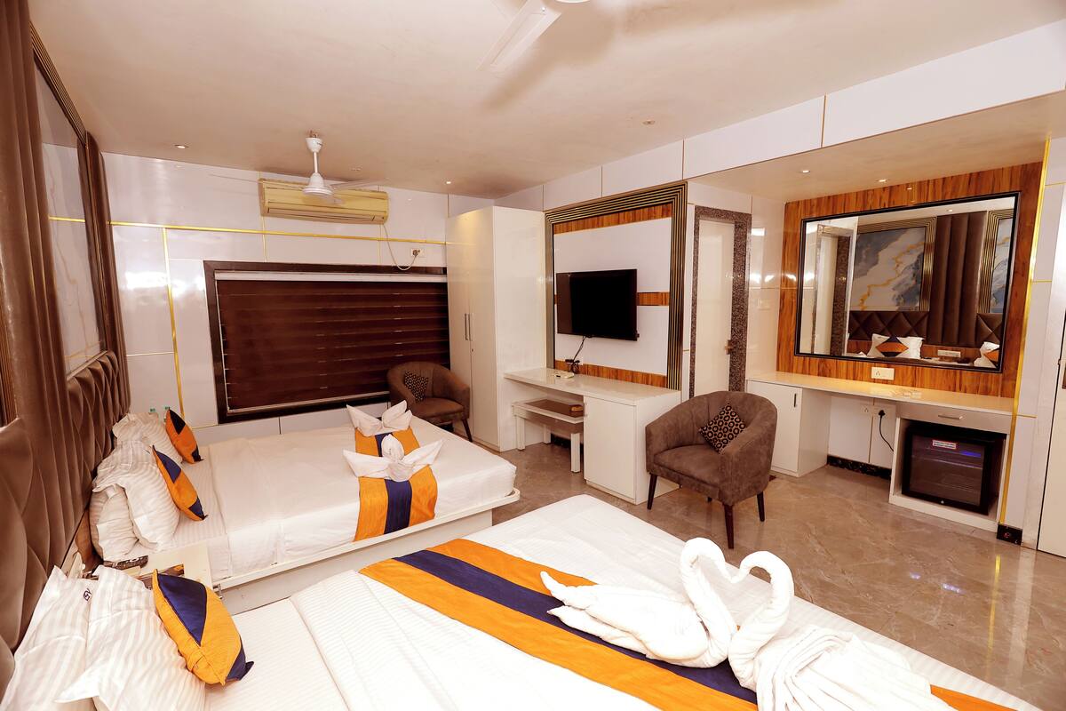 A hotel room with two beds, a TV, a desk, a chair, and a mirror.