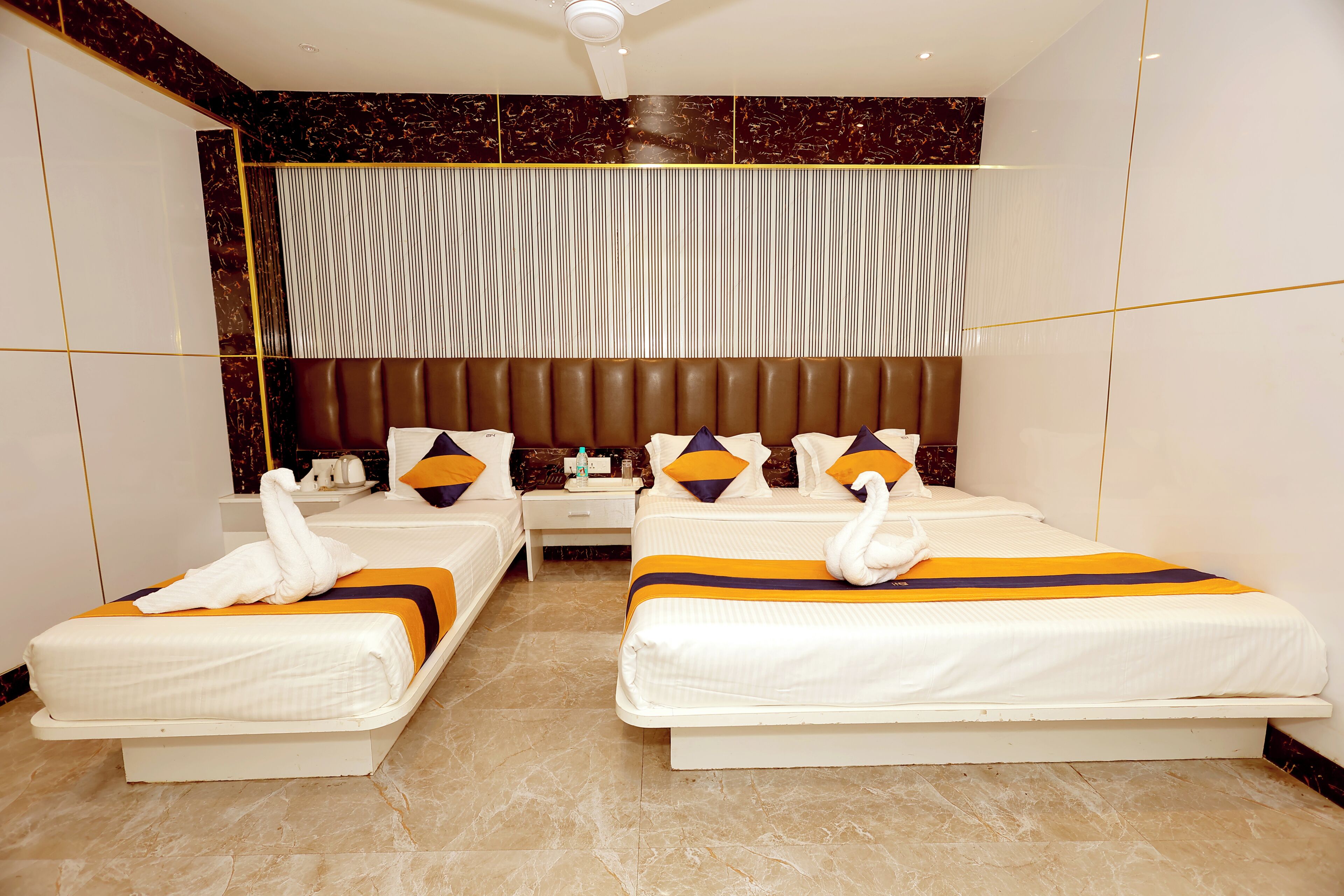 A hotel room with two beds, a marble floor, a large window with blinds, and a modern headboard.