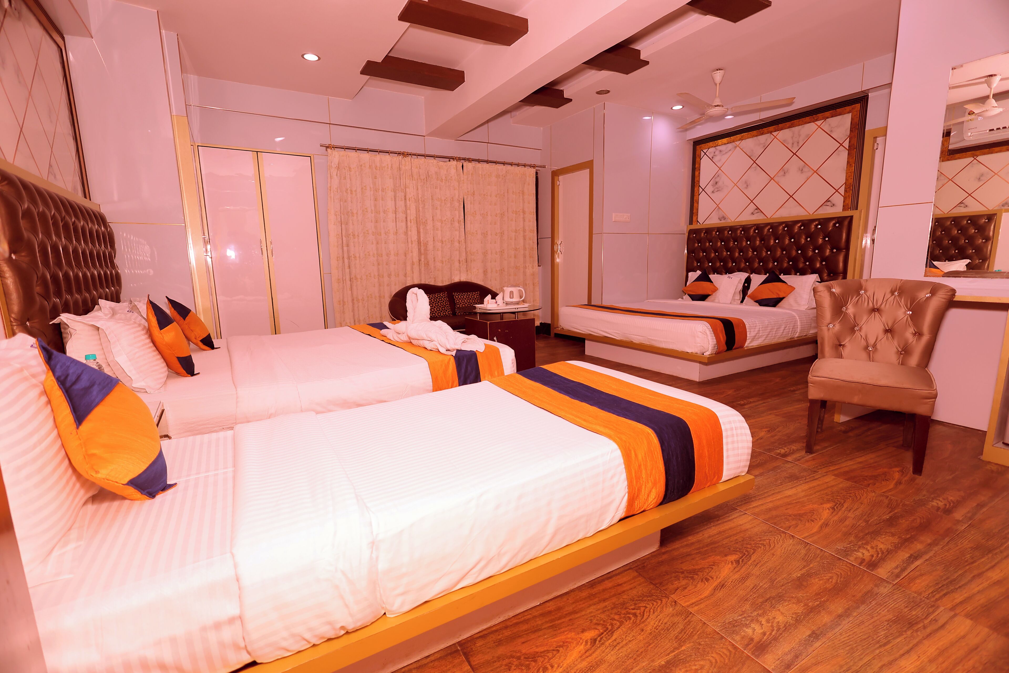 A hotel room with two beds, a wardrobe, a desk, and a chair.