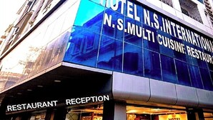 A multi-story hotel building with a prominent sign for 'HOTEL N.S. INTERNATIONAL' and a 'RESTAURANT RECEPTION' sign below.