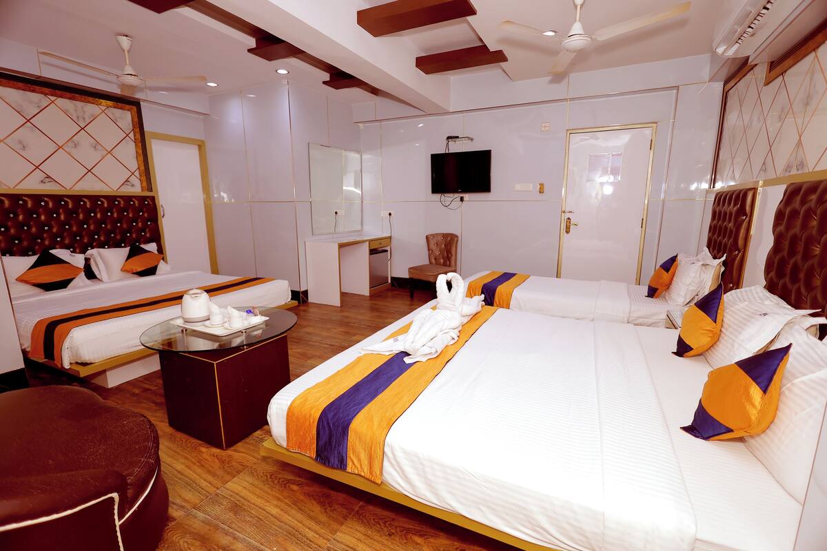 A hotel room with a large bed, a sofa, a small table, and a television.