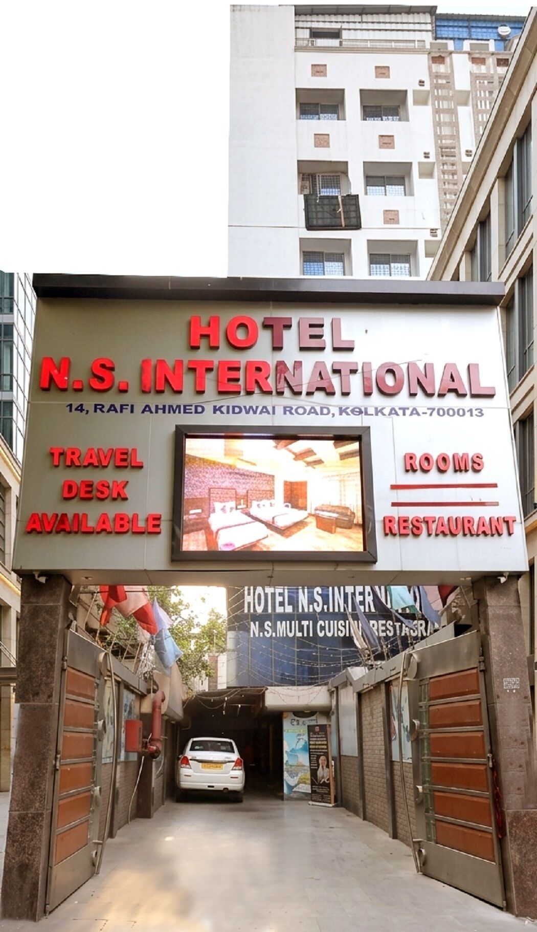 A hotel sign with 'HOTEL N.S. INTERNATIONAL' and mentions 'TRAVEL DESK AVAILABLE,' 'ROOMS,' and 'RESTAURANT.'