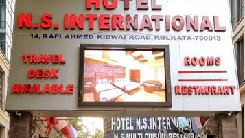 A hotel sign with 'HOTEL N.S. INTERNATIONAL' and mentions 'TRAVEL DESK AVAILABLE,' 'ROOMS,' and 'RESTAURANT.'