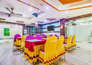 Un salón de conferencias con una larga mesa, sillas amarillas y un mantel rojo.