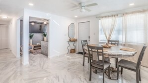 Uma sala de jantar com uma mesa redonda, cadeiras e um ventilador de teto.