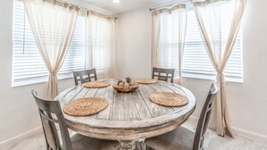 Uma sala de jantar com uma mesa de madeira redonda, quatro cadeiras e um jogo americano de fibra central.