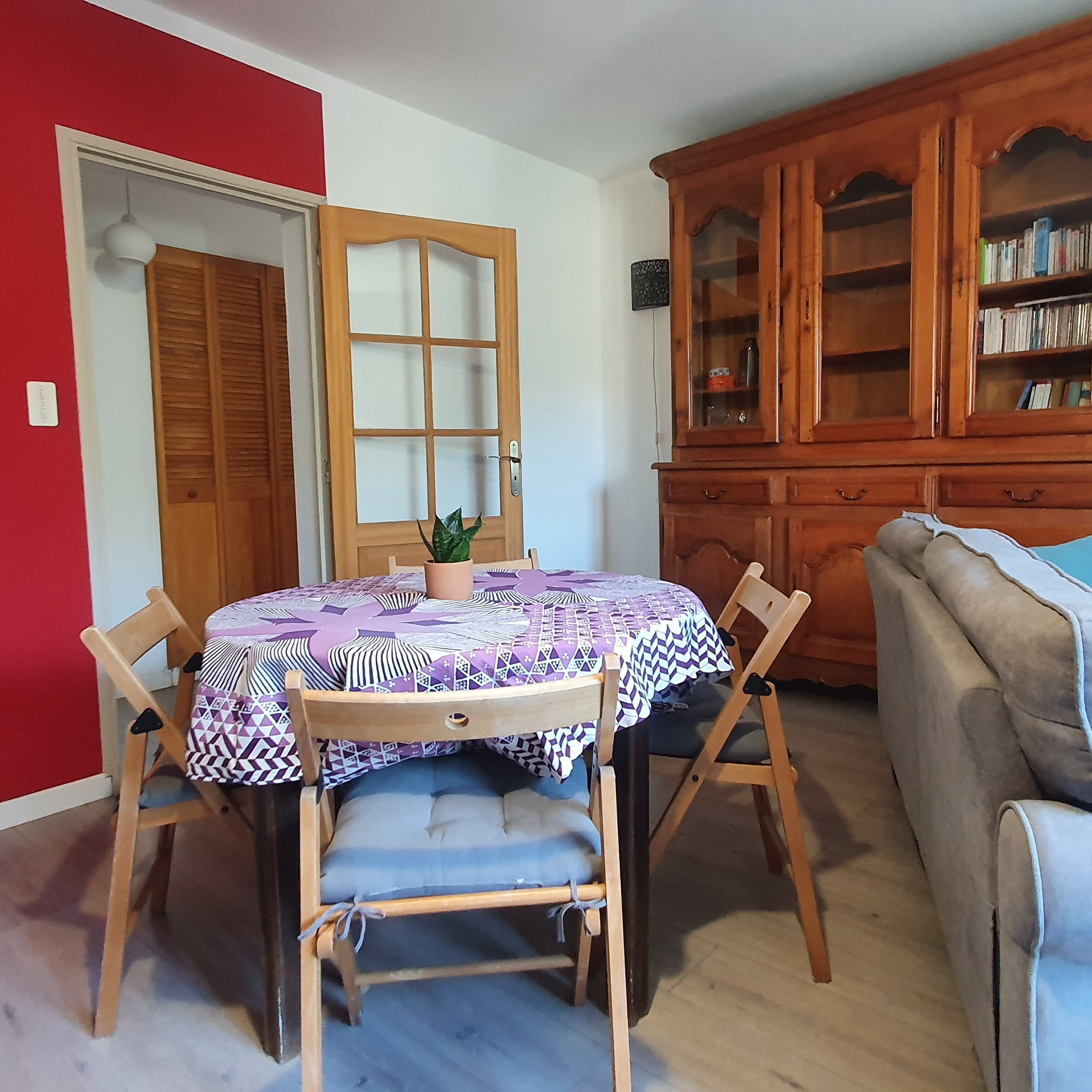A dining area with a round table, chairs, a cabinet with glass doors, and a sofa.