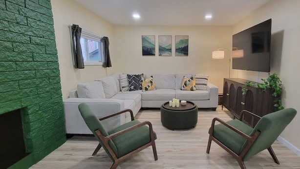 A living room with a sectional sofa, two armchairs, a coffee table, a flat-screen TV, and artwork on the walls. - Charming Pocono Bungalow with Firepit, Grill, Outdoor seating, Walk to Lake (Pocono Lake)
