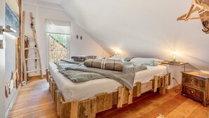 Ein Schlafzimmer im Loft-Stil mit schrägem Dach, einem Holzbettgestell und einem kleinen Nachttisch mit Lampe.