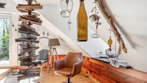 Ein modernes Loft mit schrägem Dach, einem Holzstuhl, einer Lampe und dekorativen Flaschen.