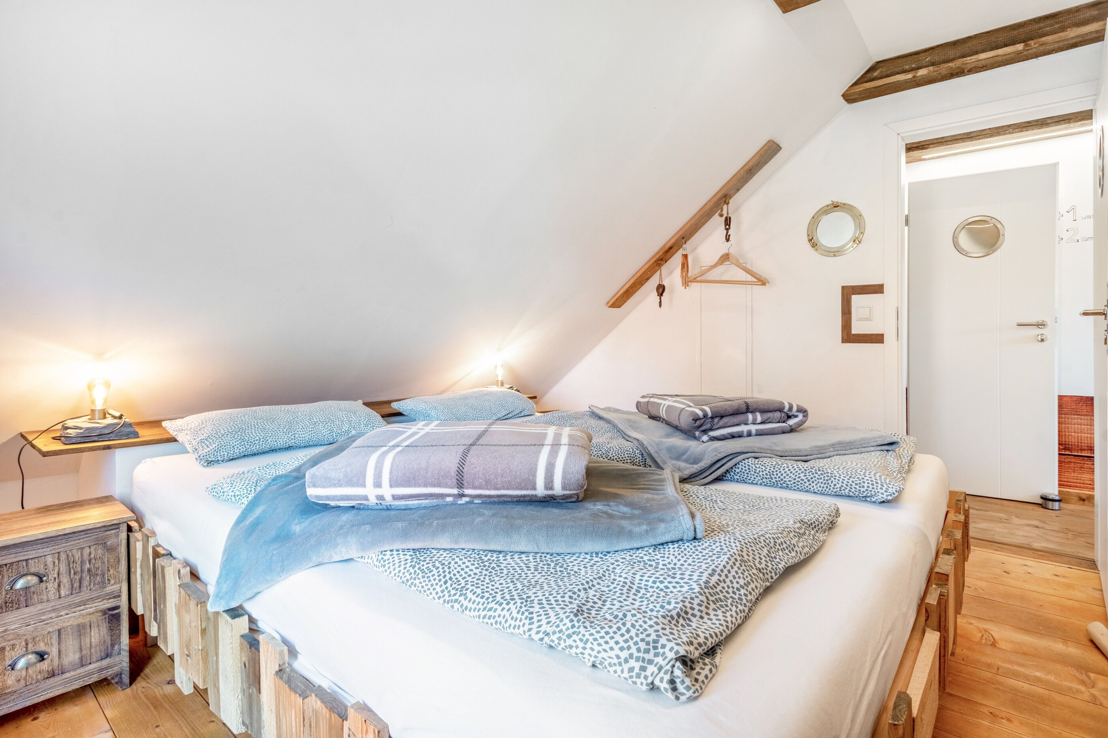 A bedroom with a bed, wooden headboard, bedside tables, and a hanging light fixture.