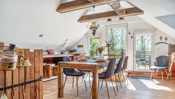 Ein Essbereich mit Holztisch, Stühlen und einer rustikalen Küche im Hintergrund.