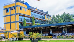 A multi-story hotel with balconies, outdoor seating, and a garden area. - The Grand Brystal Hotel (Busia)