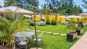 A patio area with outdoor seating, umbrellas, and potted plants. - The Grand Brystal Hotel (Busia)