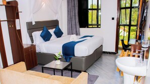 A bedroom with a bed, bedside table, and a view of the outdoors. - The Grand Brystal Hotel (Busia)