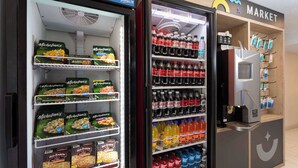A vending machine with snacks and drinks, a microwave, and a coffee machine. - 2 Queen | Howard Johnson | Room for Whole Crew! | Near Disney w/ Free Shuttle (Kissimmee)