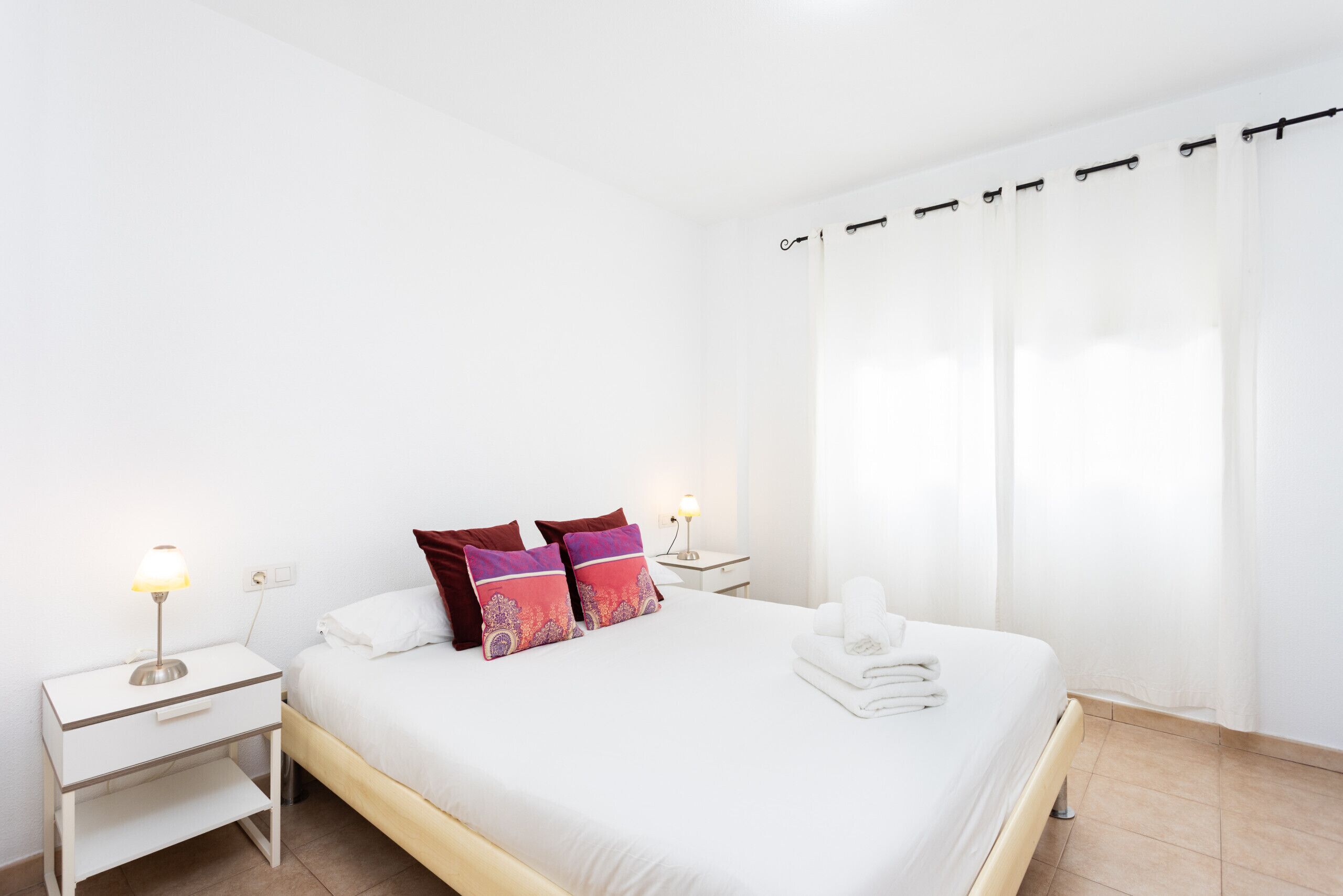 Ein sauberes, modernes Hotelzimmer mit einem Einzelbett, zwei Nachttischen und einem Beistelltisch.