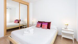 A hotel room with a large mirror, a bed with white linens, colorful pillows, a bedside table with a lamp, and a nightstand with a lamp. - Sea, Sun & Relax in Alcalá (Guía de Isora)