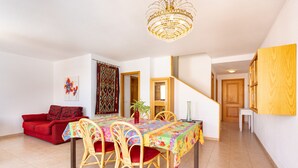 A dining area with a table, chairs, a chandelier, a red sofa, and a staircase. - Sea, Sun & Relax in Alcalá (Guía de Isora)