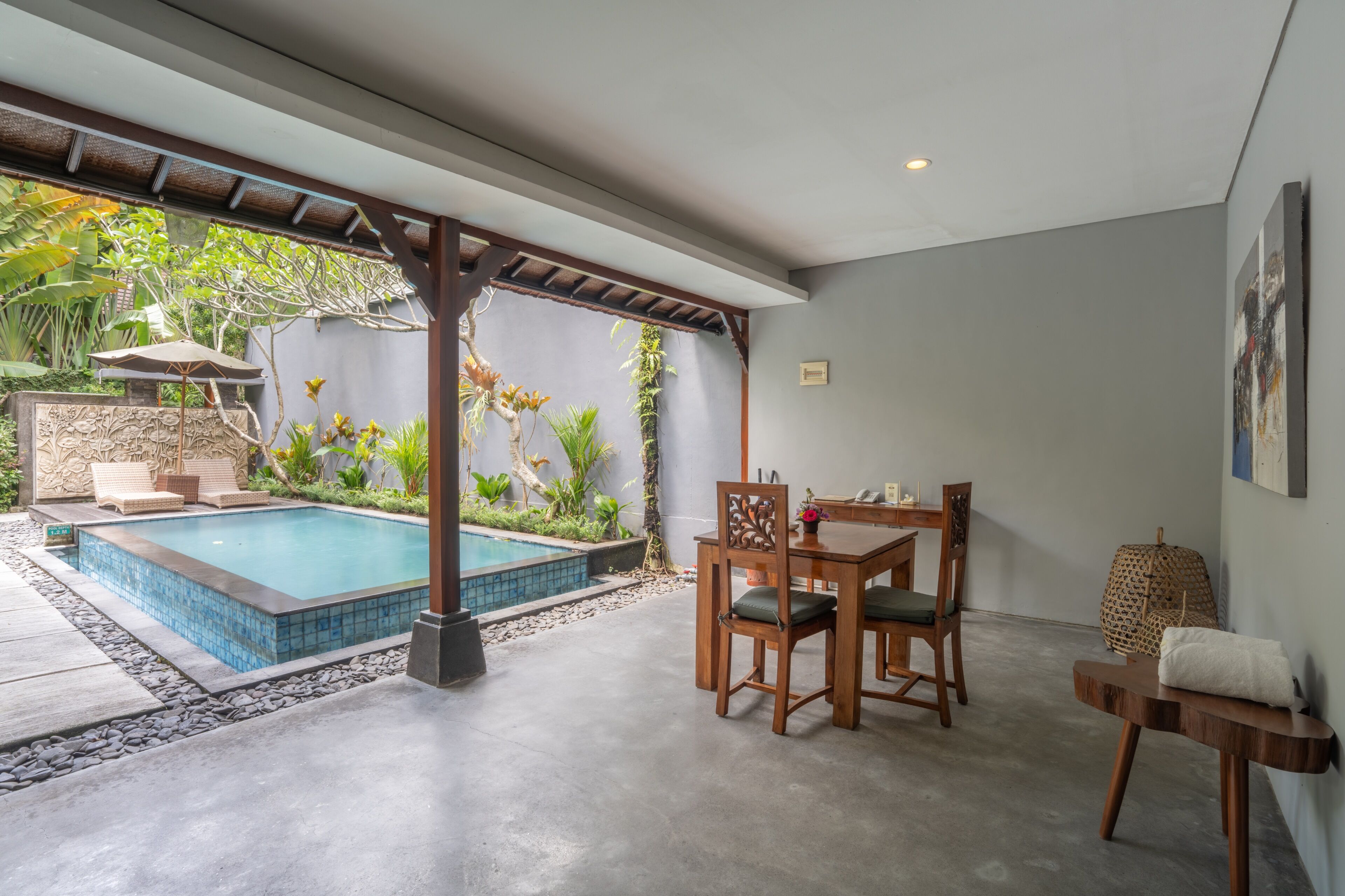 A pool area with a pergola, a dining table with chairs, and a small table with a towel.