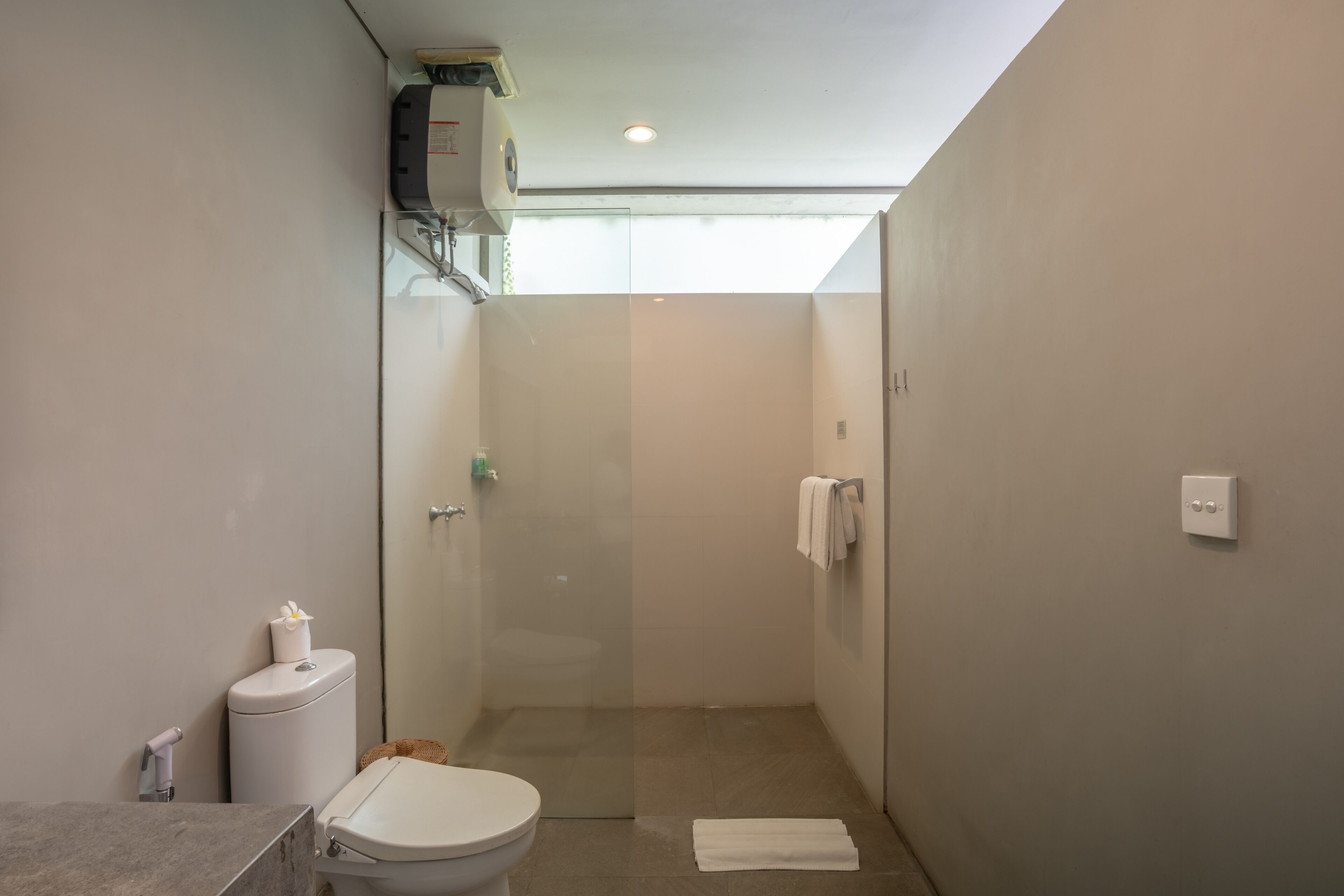 Een moderne badkamer met toilet, douche en wastafel.
