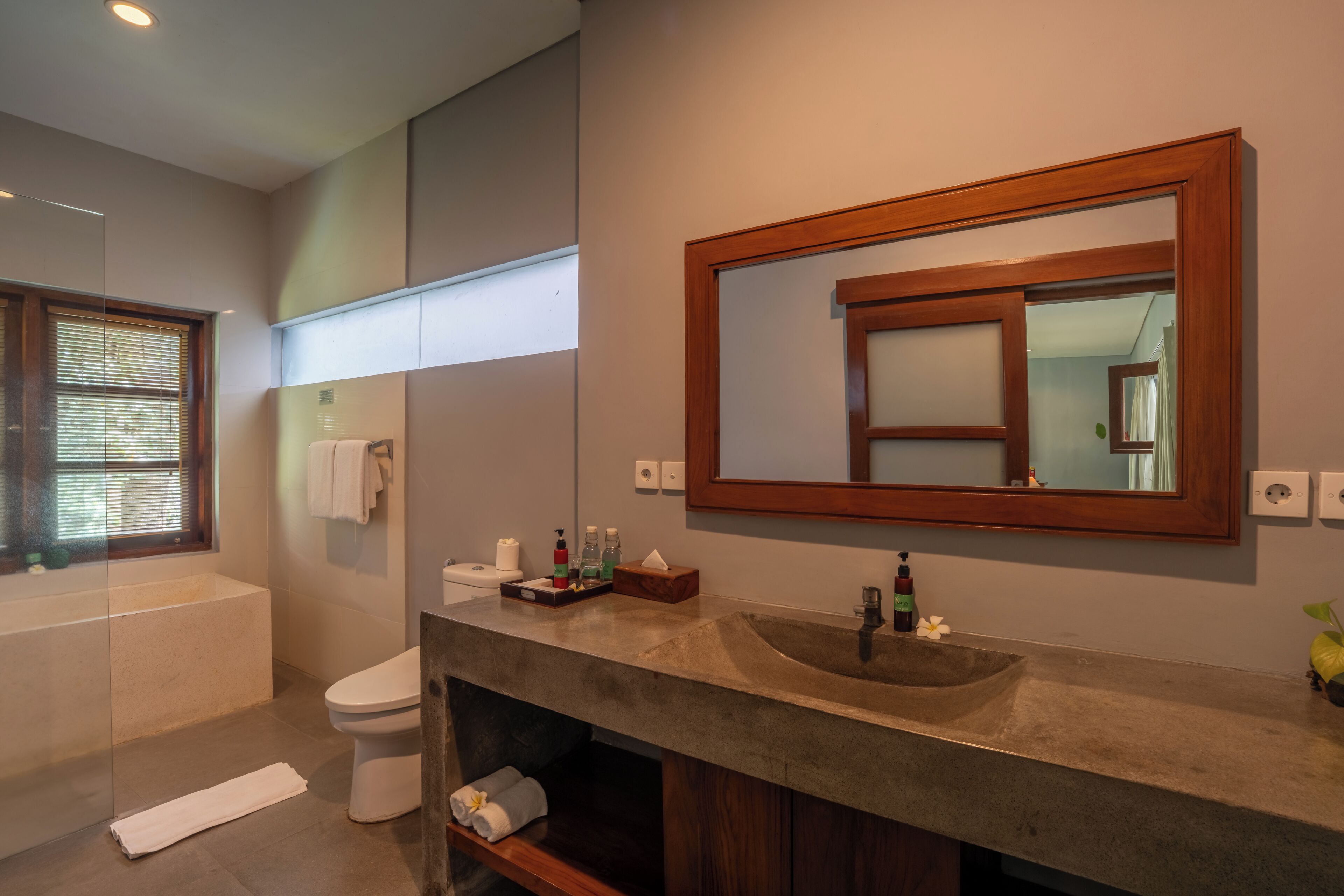 Un baño moderno con bañera, inodoro y tocador con un espejo grande.