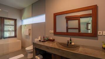 Un baño moderno con bañera, inodoro y tocador con un espejo grande.
