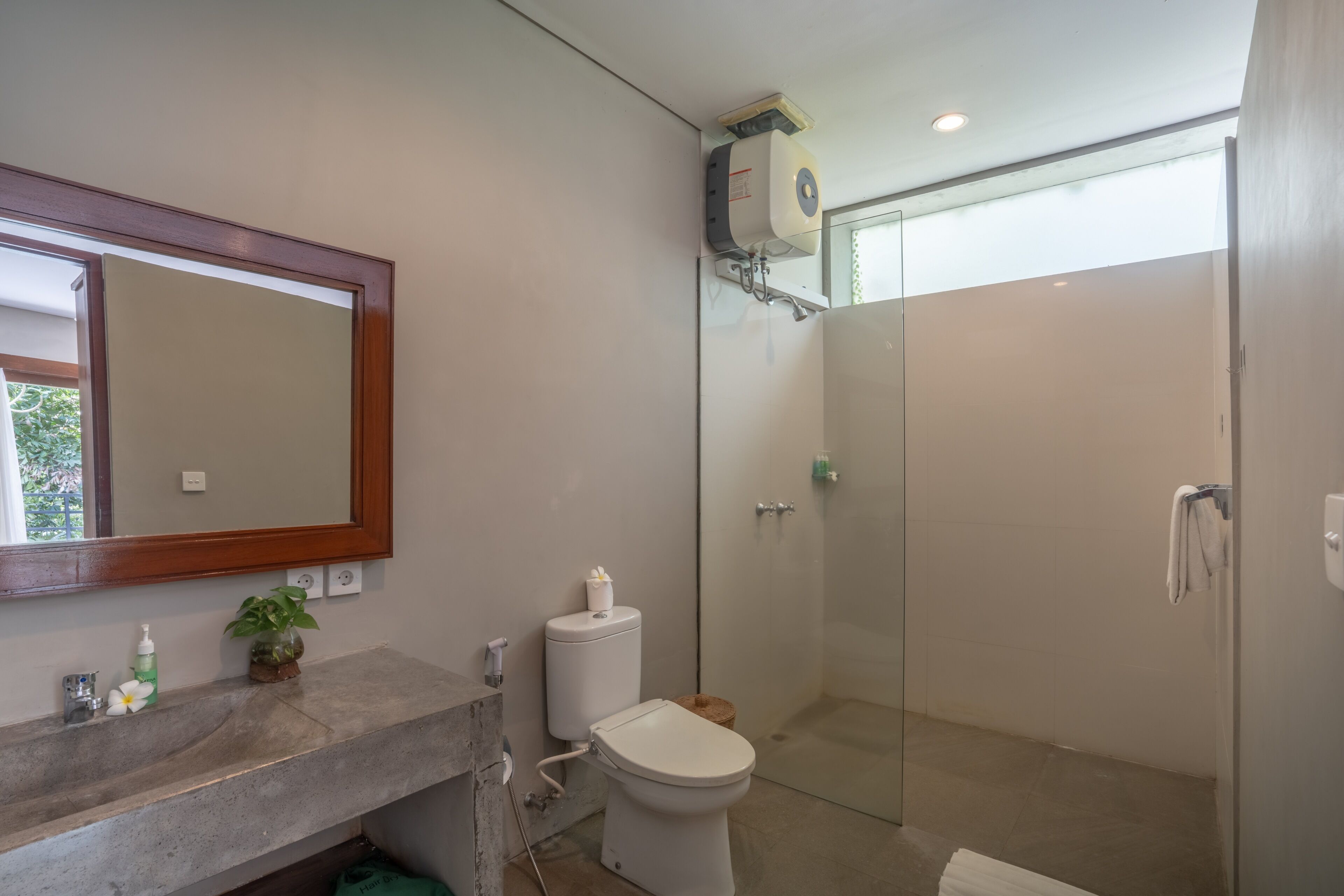 A bathroom with a large mirror, a toilet, a shower, and a sink.