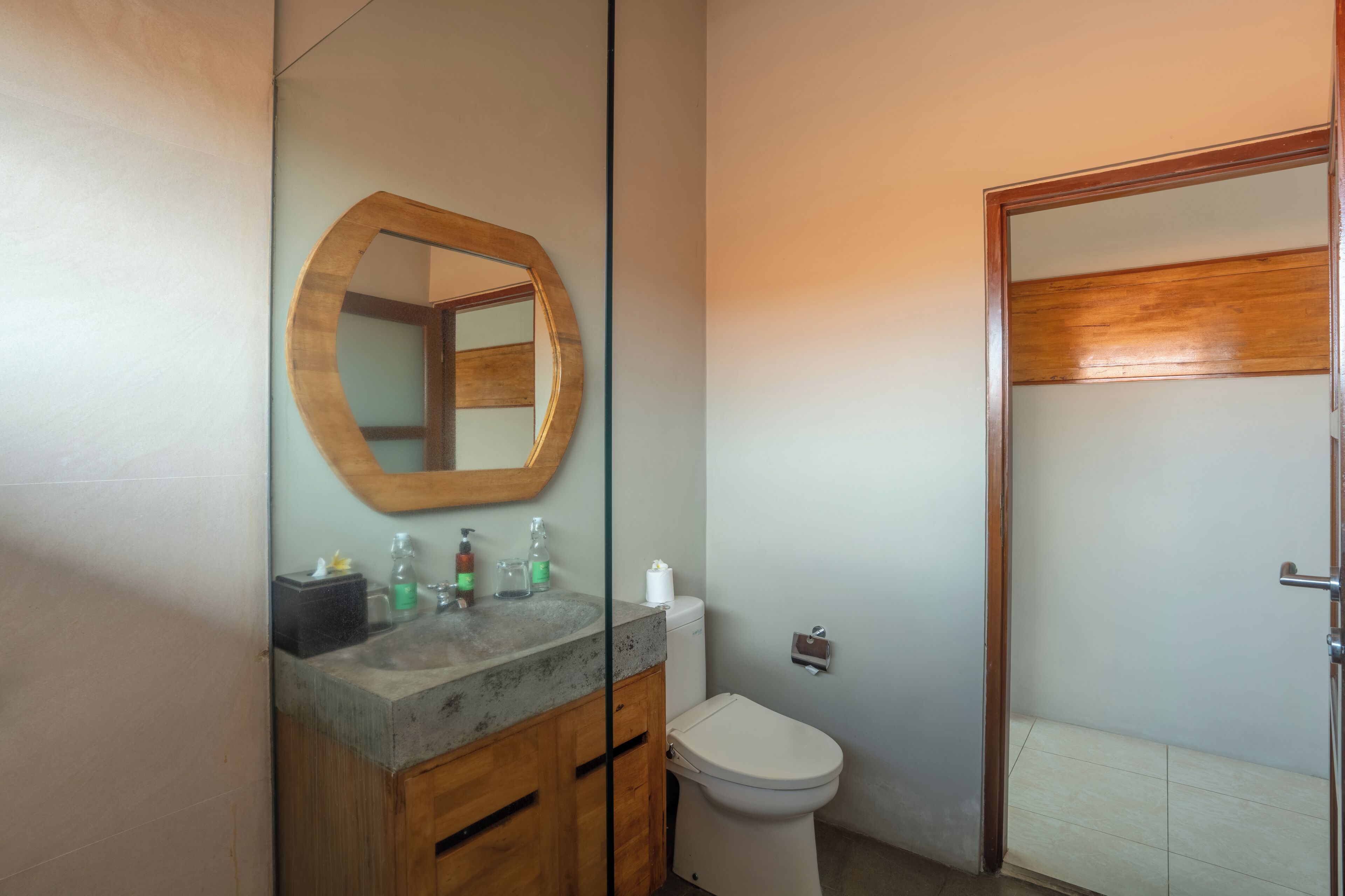A bathroom with a wooden vanity, a toilet, and a mirror.