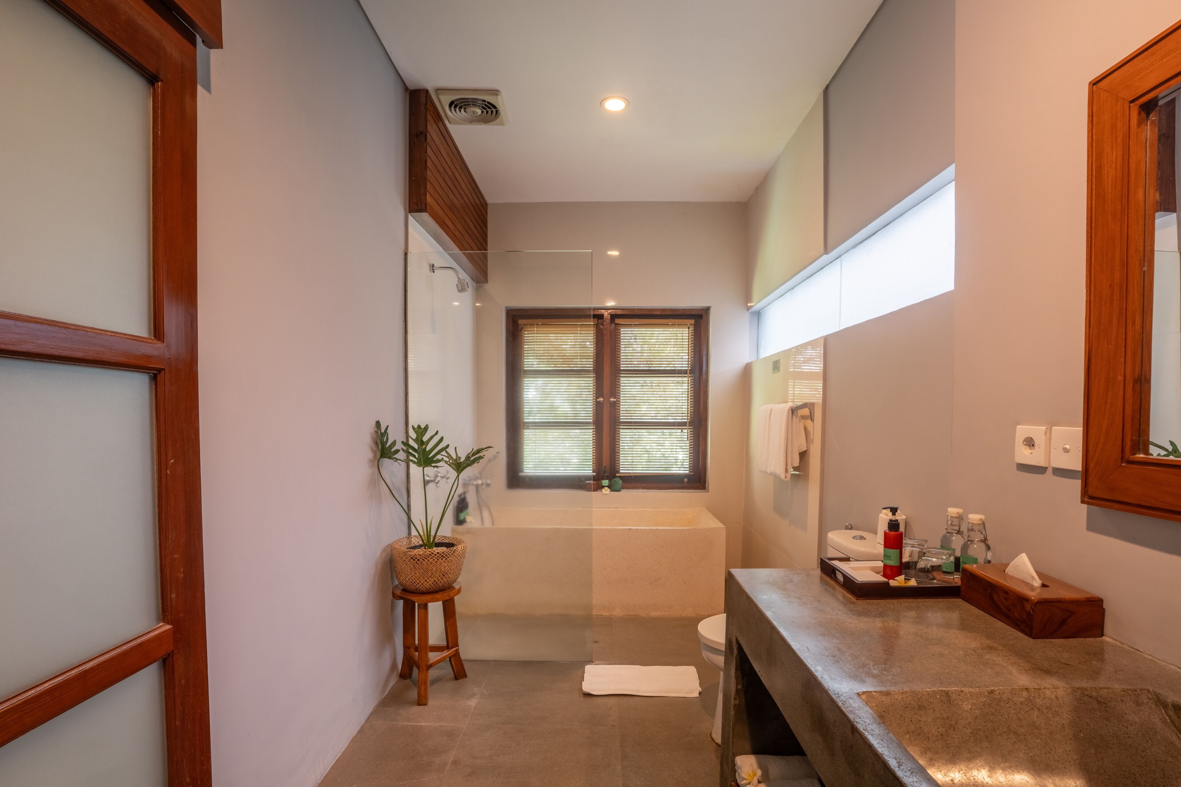 A modern bathroom with a bathtub, a shower, a sink, and a window with blinds.