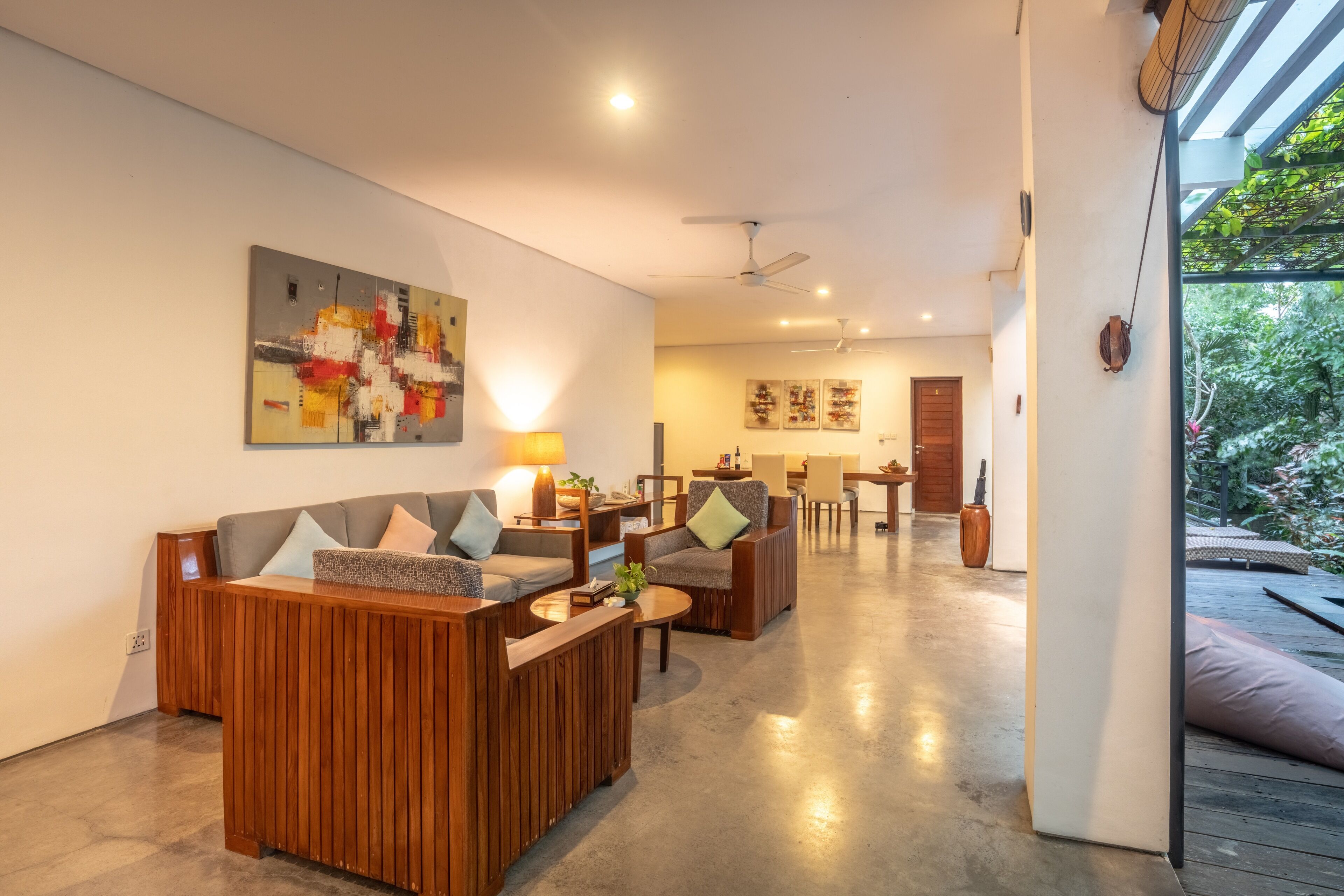 A modern living room with a wooden sofa set, a coffee table, and a painting on the wall.