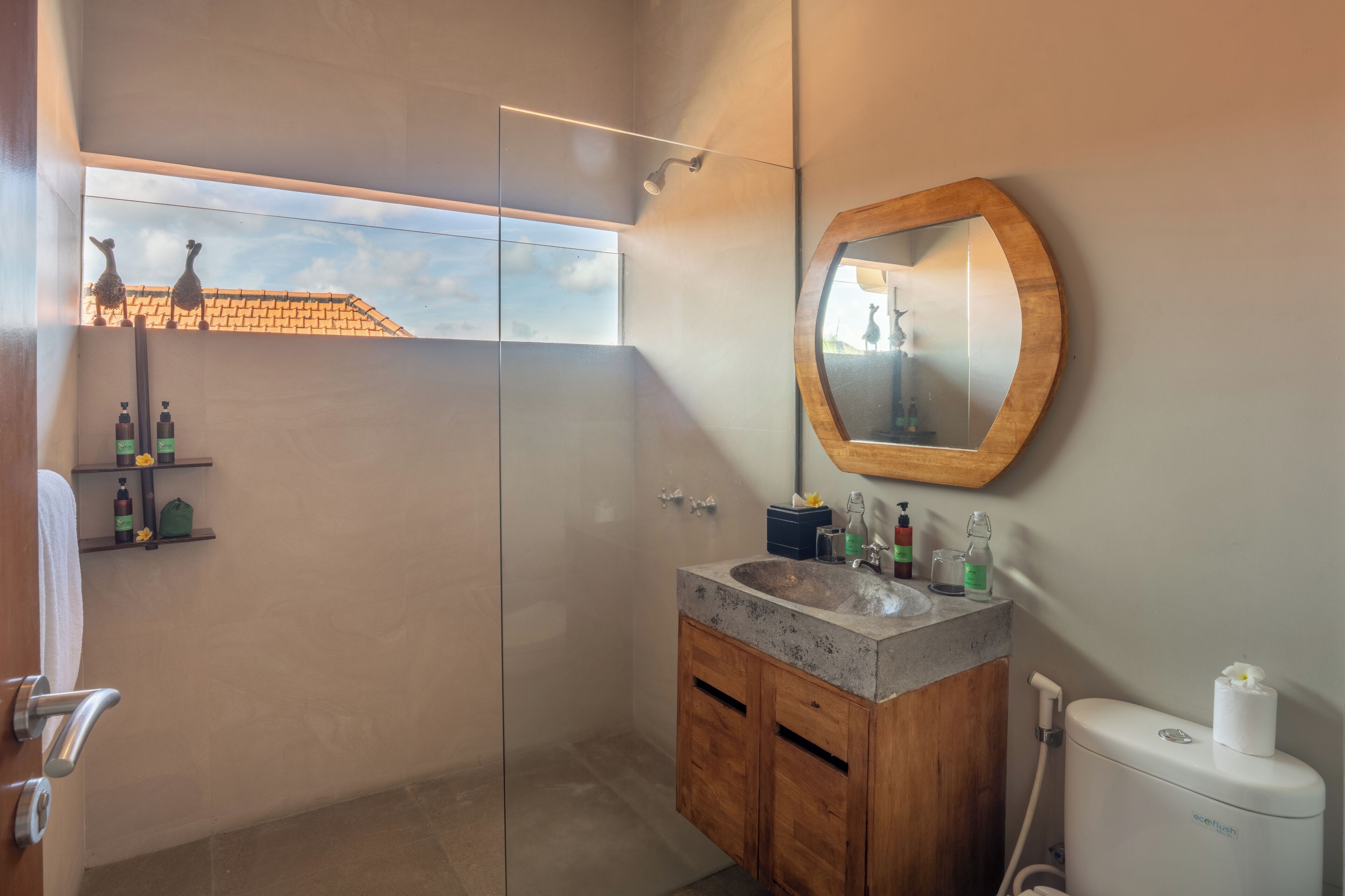 A modern bathroom with a glass shower enclosure, a wooden vanity with a sink, and a large mirror.