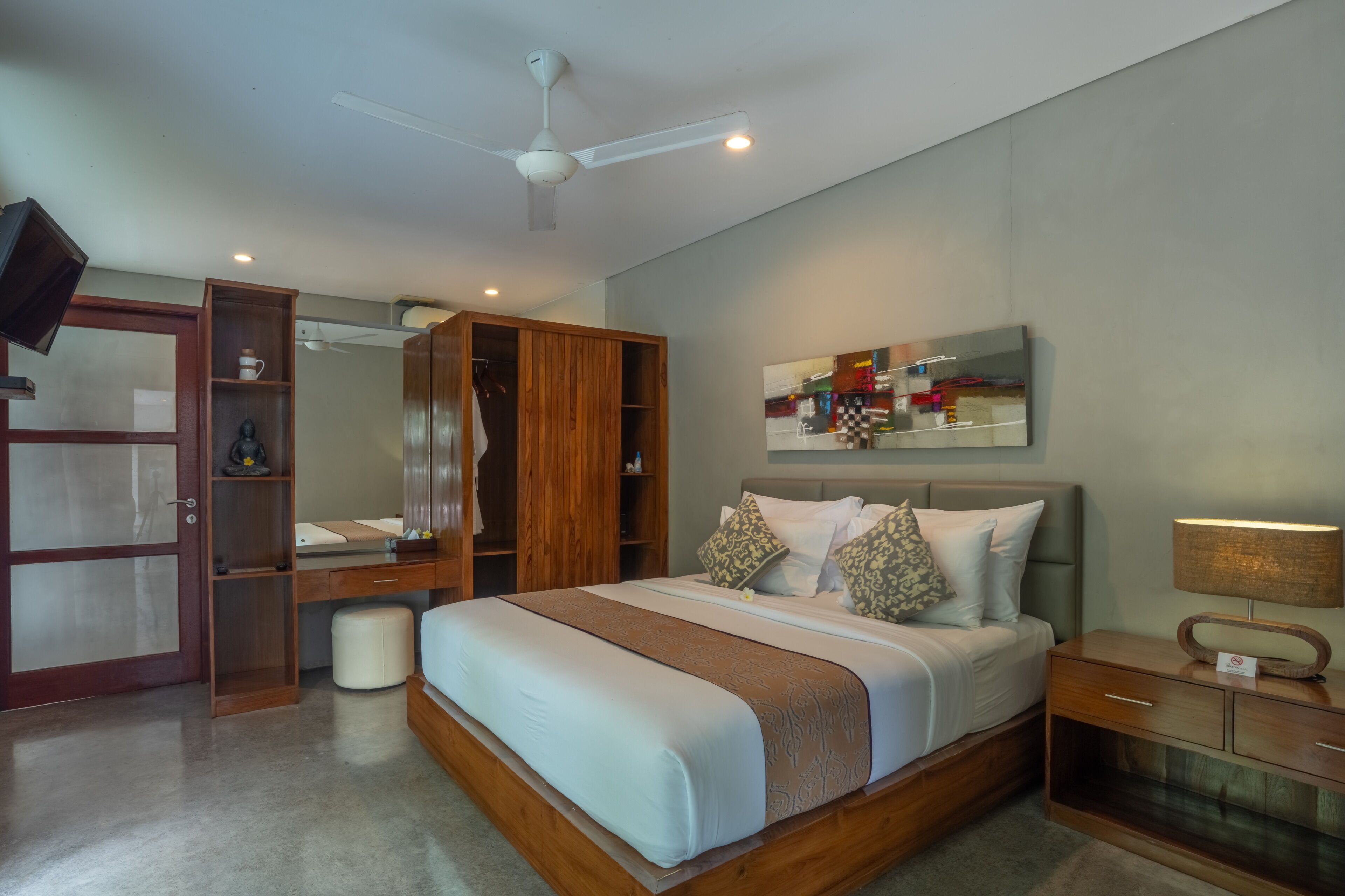 A bedroom with a bed, wooden wardrobe, bedside table, and a ceiling fan.