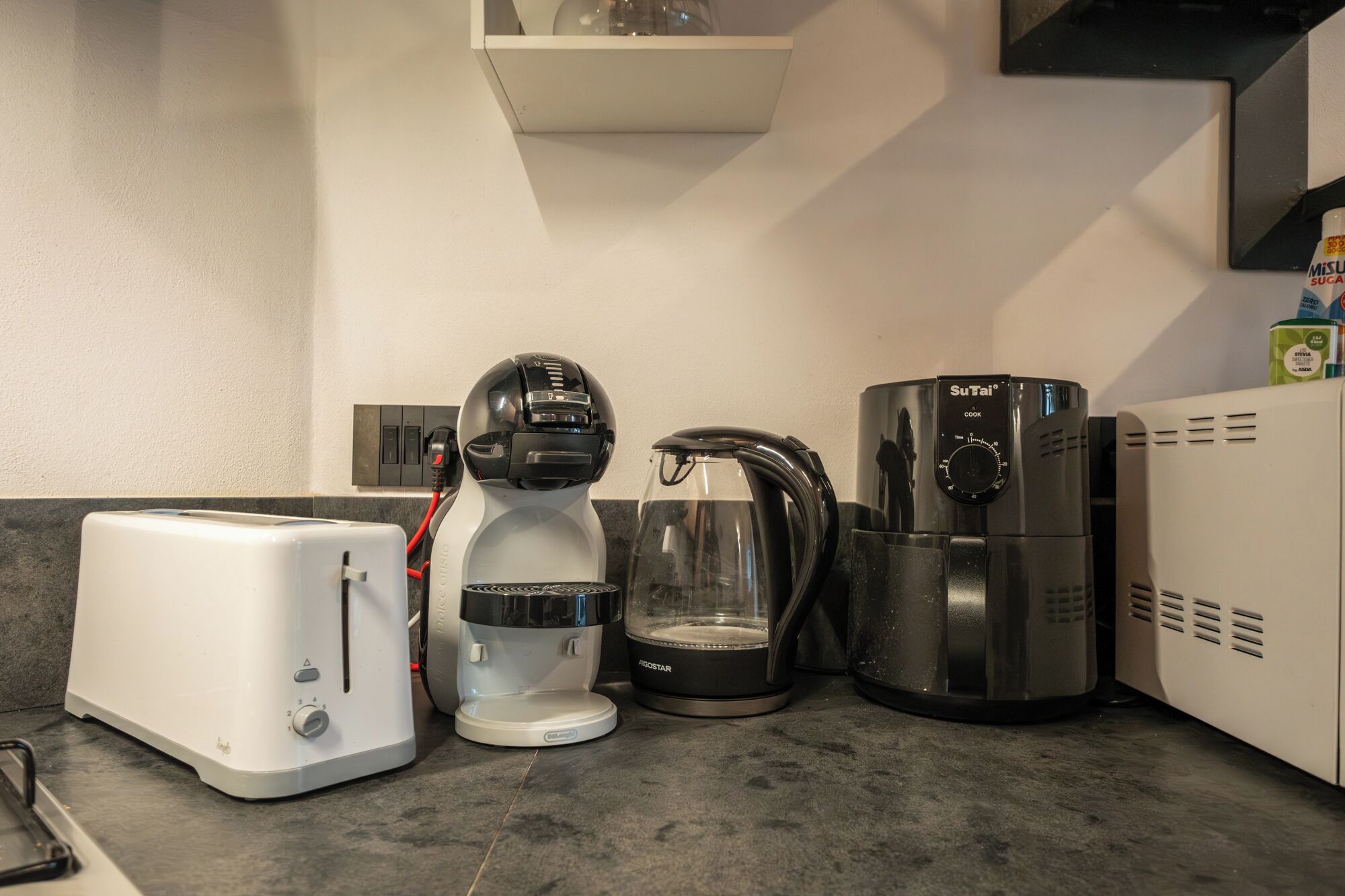 Une cuisine équipée d’un grille-pain, d’une machine à café, d’une bouilloire et d’un cuiseur à riz.