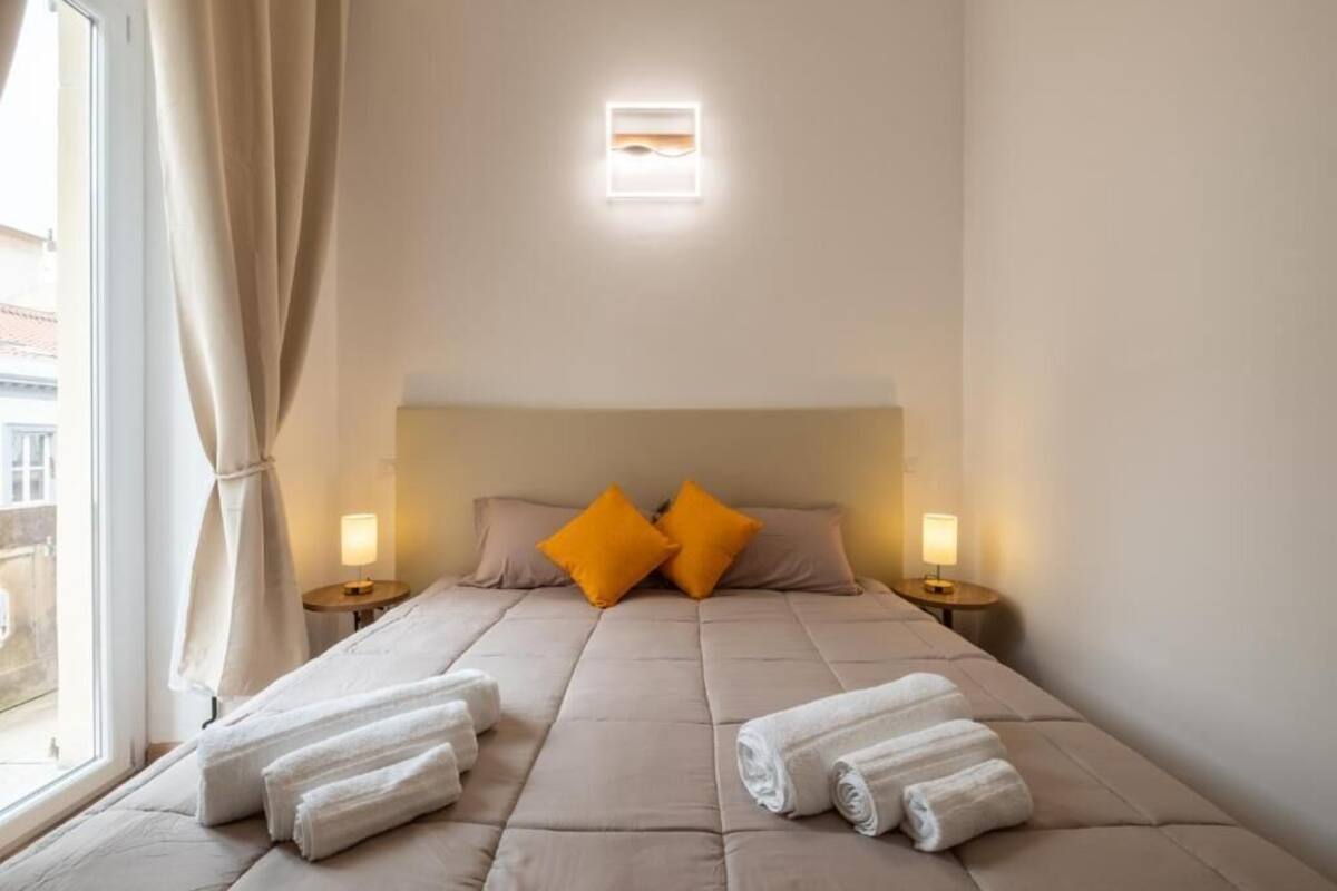 Ein Hotelzimmer mit einem Bett, zwei Kissen, zwei Nachttischlampen und Handtüchern auf dem Bett.