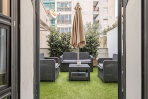 Un espace patio aménagé avec du mobilier d’extérieur, une table et un grand parasol.