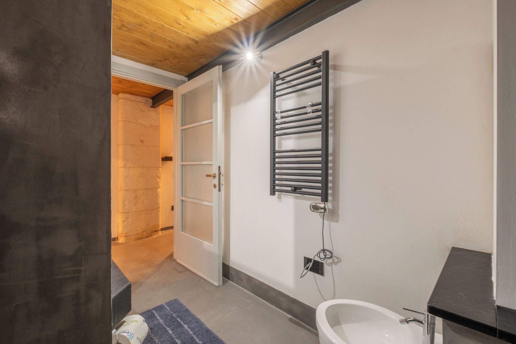 Ein Badezimmer mit einer weißen Badewanne, einem Handtuchhalter und einer Tür zu einem anderen Raum.