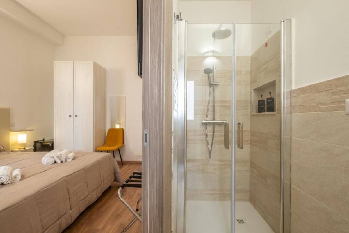Ein Hotelzimmer mit Bett, Stuhl, Dusche und Kleiderschrank.