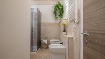 Un baño moderno con ducha, inodoro, bidé y un perchero para toallas.