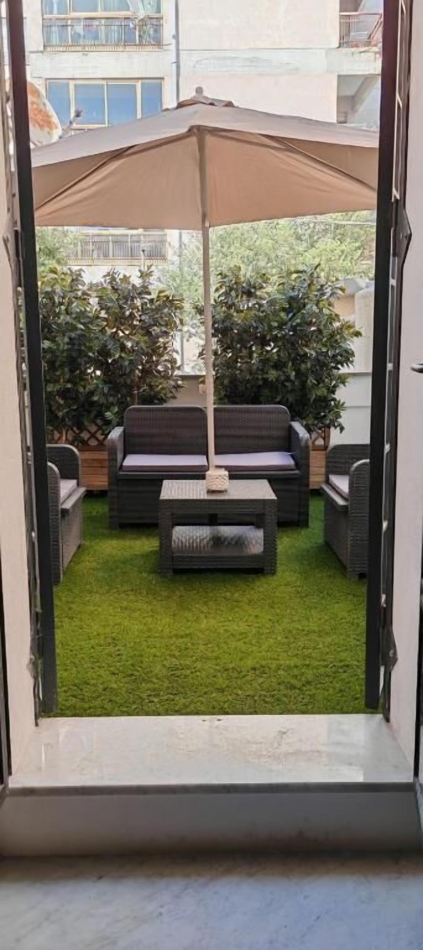 Un patio con mobiliario exterior, un dosel y césped artificial verde.
