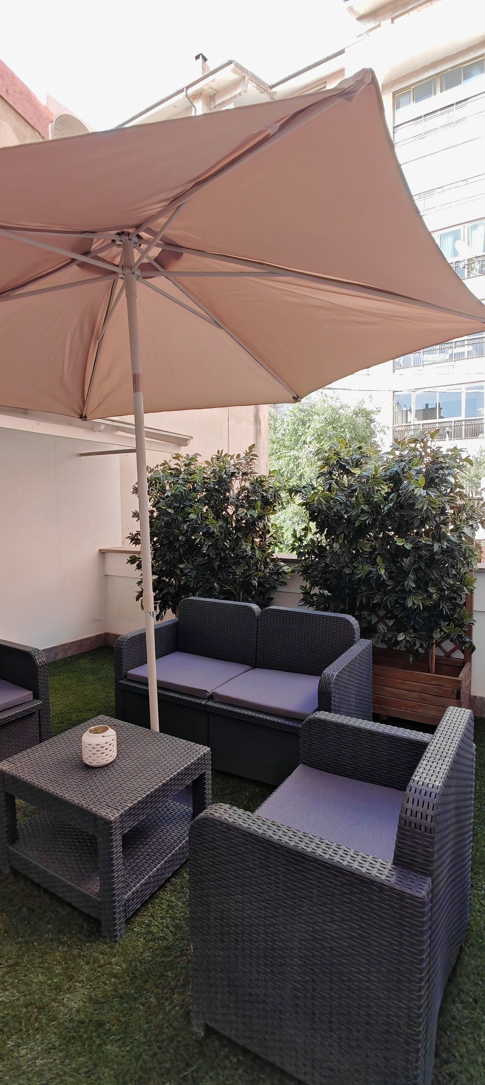A patio area with outdoor furniture, including a sofa and chairs, under a large umbrella.