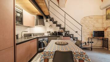 Una cocina moderna con comedor, una escalera y una pared de piedra.