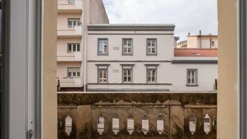Vista di un edificio con numerose finestre e balconi, un parapetto in pietra e cielo sereno.
