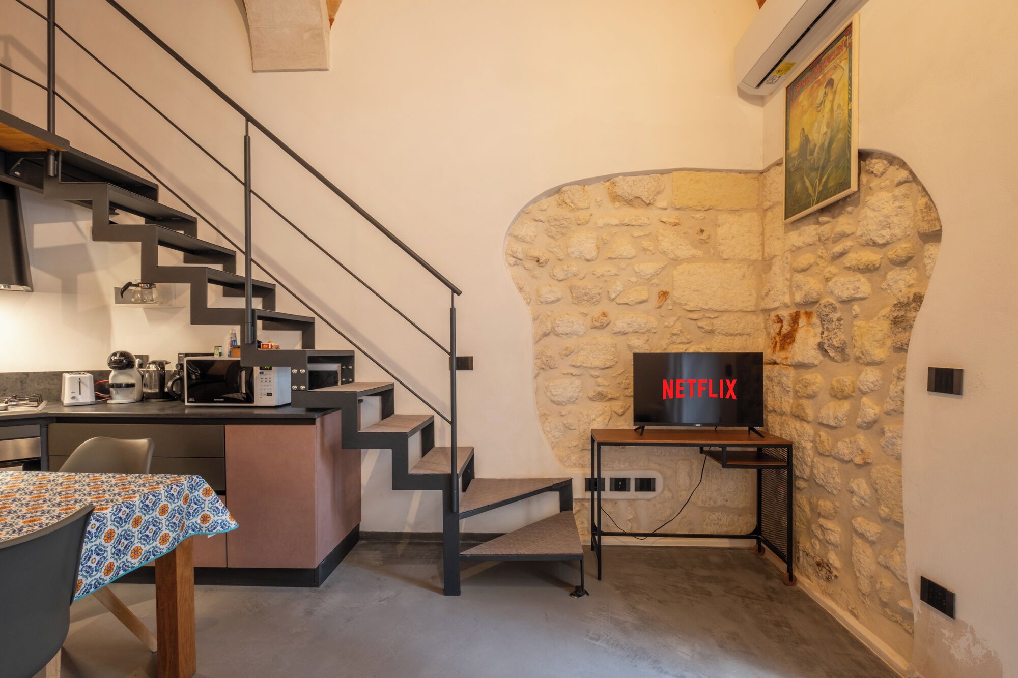 Una cocina moderna con pared de piedra, una escalera y un letrero de Netflix.