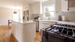 A modern kitchen with white cabinetry, a central island, a gas stove, and a window with a view. - Top Rated w/Free Street Parking+ 2 King Beds 1 Single +In Unit-Laundry +1.5 Bath (Chicago)